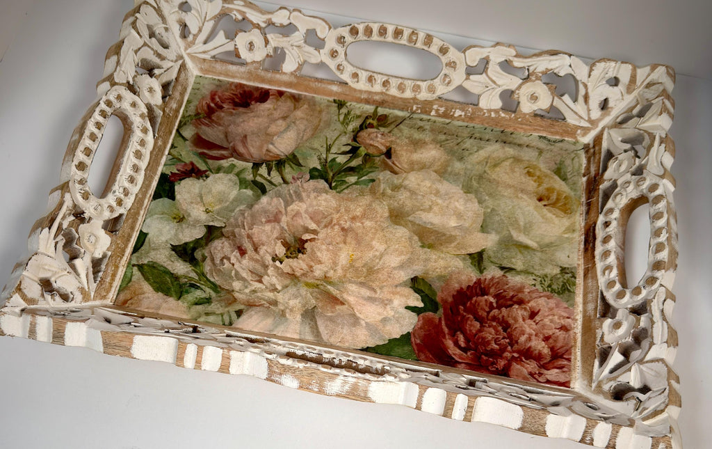 a decorative white tray with an ornate frame, displaying a floral arrangement of various flowers.