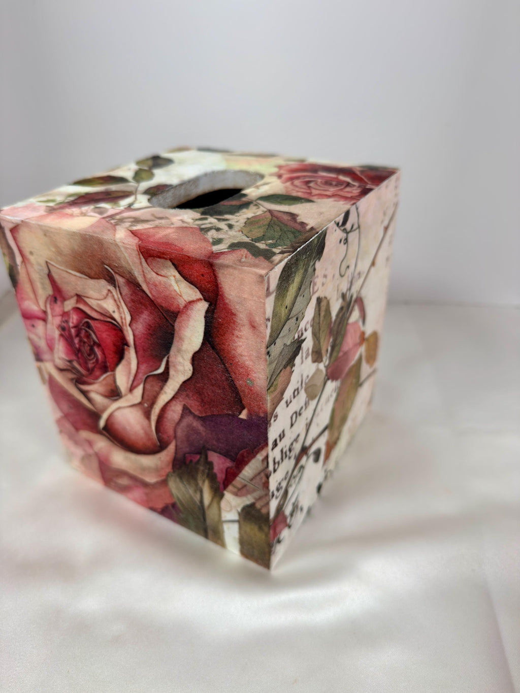 A decorative box with a floral pattern, featuring a large rose and other colorful flowers.