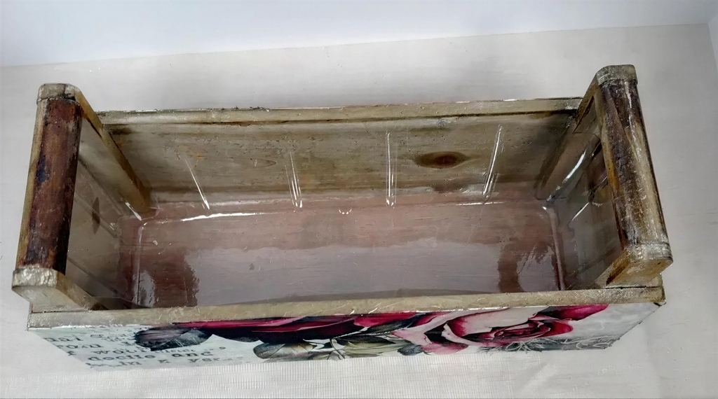a wooden box with a floral design on the front, sitting on a white surface.