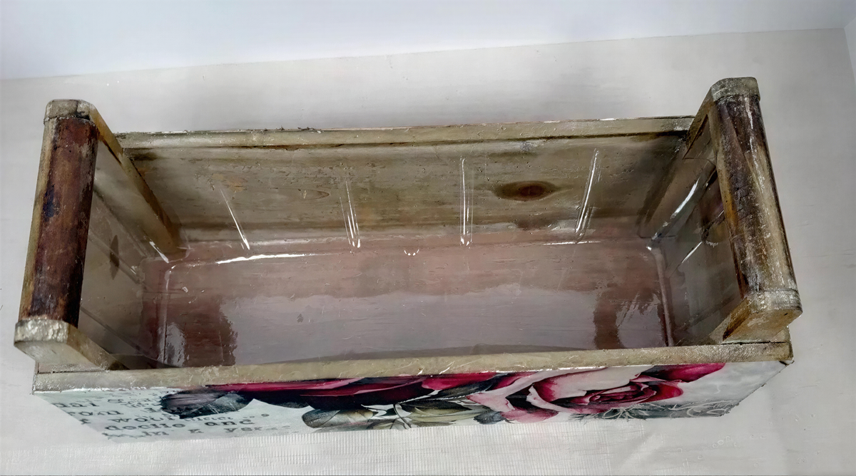 a wooden box with a floral design on the front, sitting on a white surface.