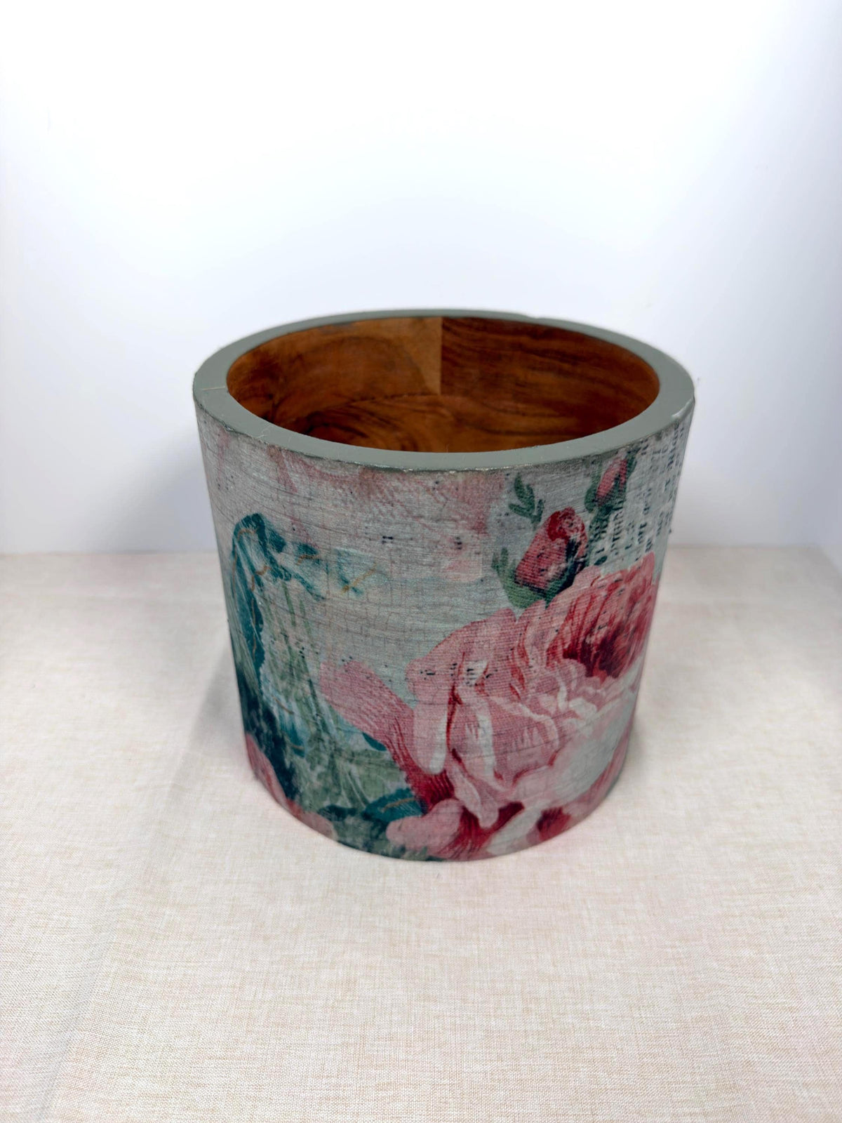 a cylindrical object with a floral pattern on it, placed on a light-colored surface.