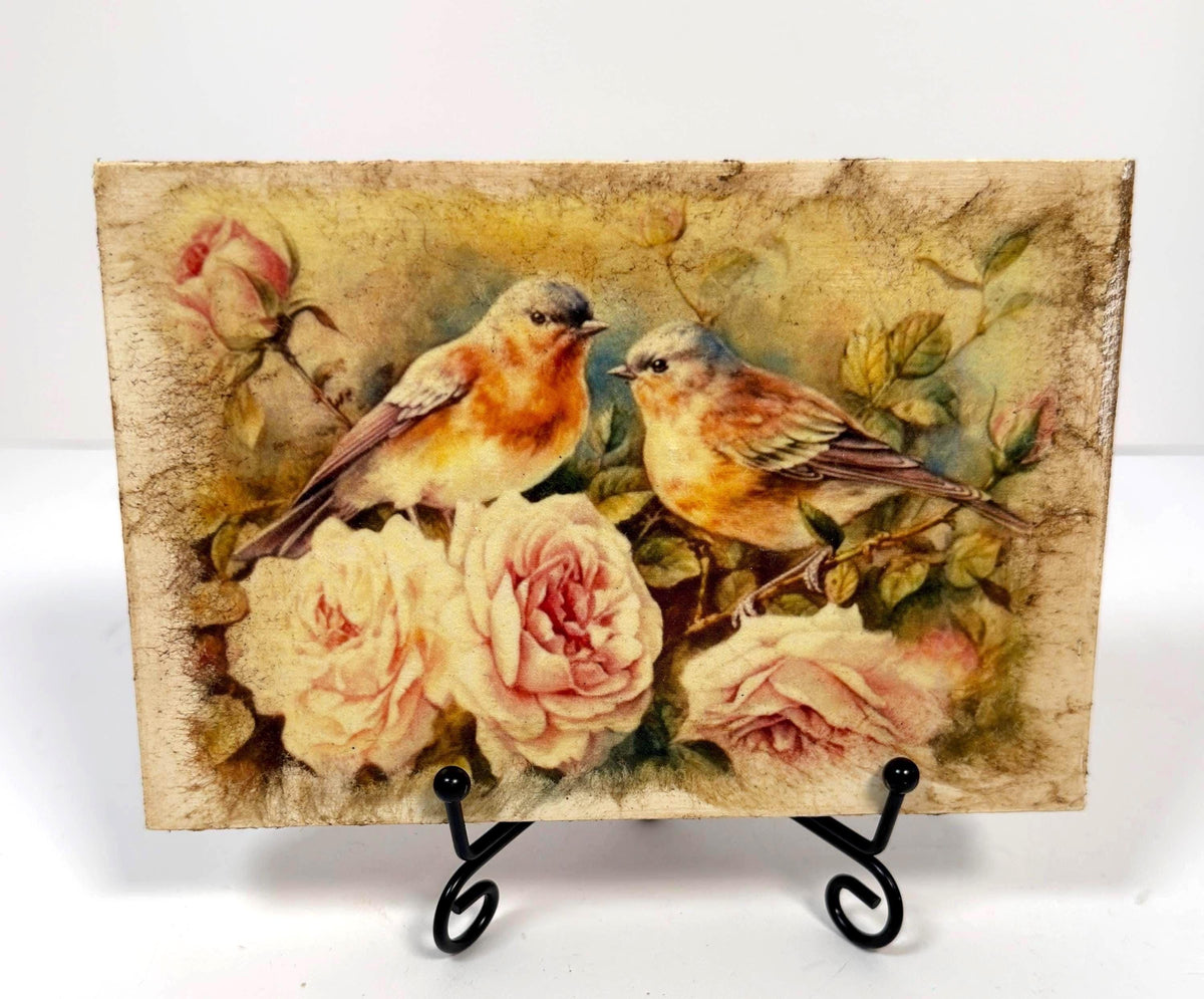 two birds perched on a branch with pink roses, surrounded by lush greenery.