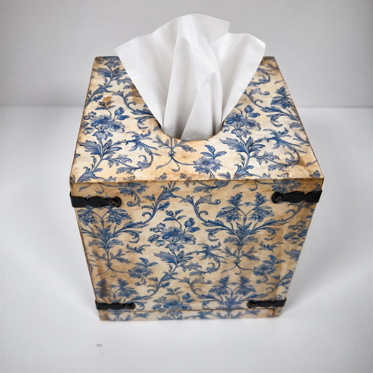 A decorative tissue box with a blue floral pattern and a white tissue paper dispenser.
