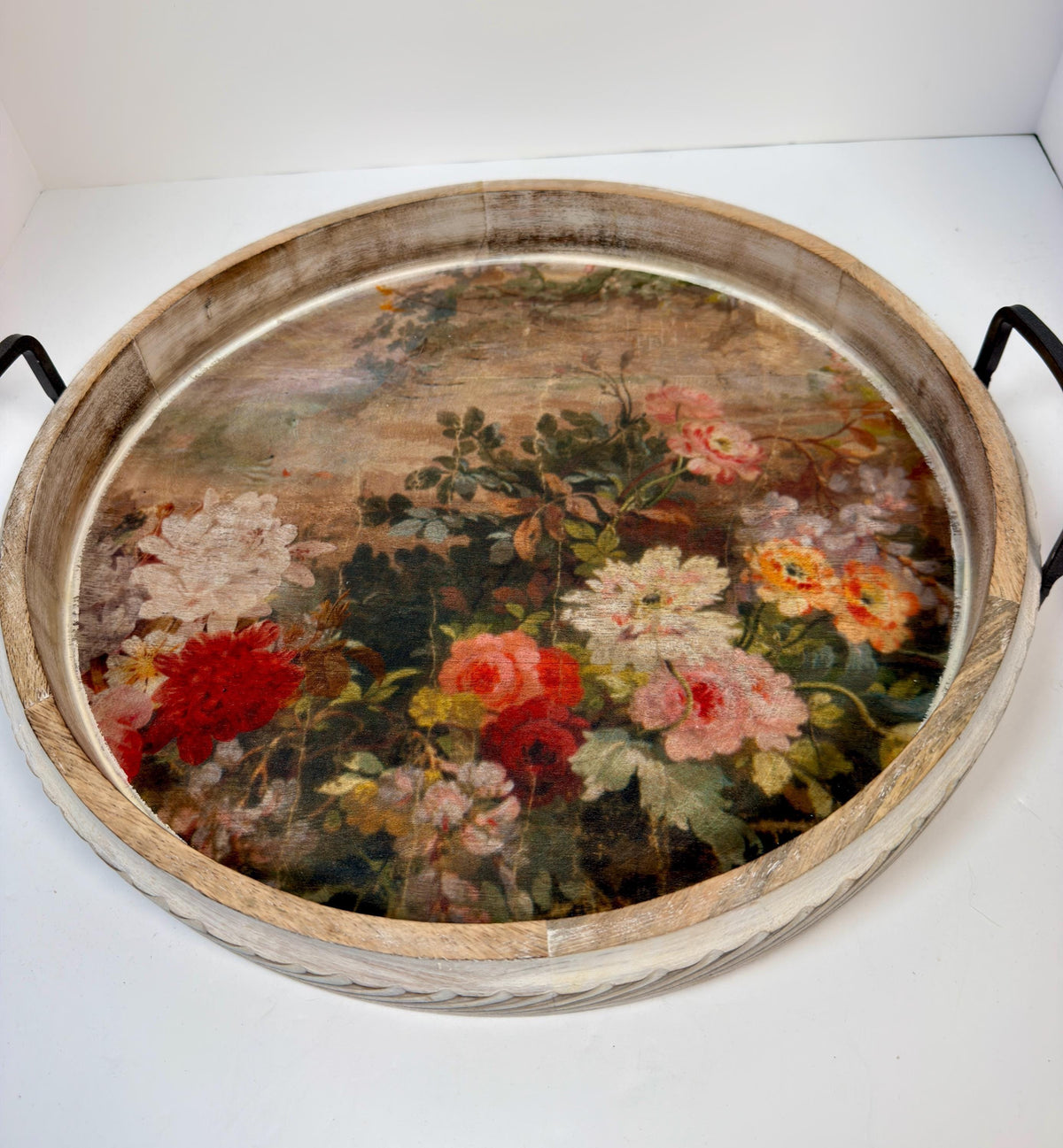a round wooden tray with a floral design on it.