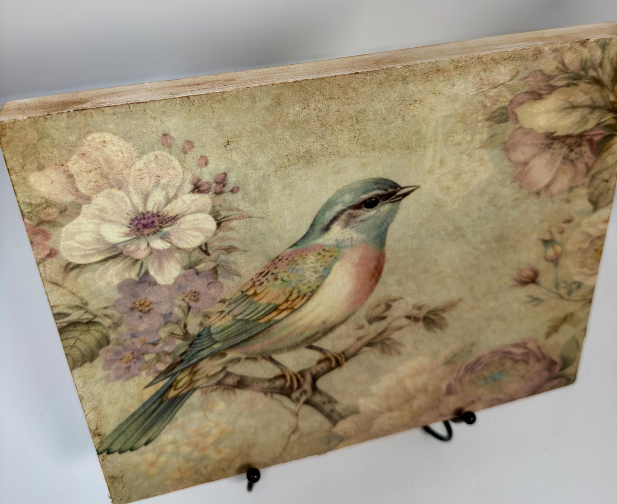 a close-up of a wooden block with a painting of a colorful bird perched on a branch, surrounded by flowers.