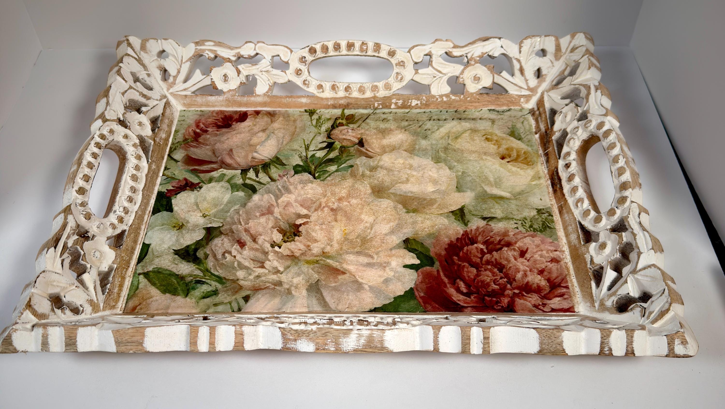 A decorative white tray with an intricate floral design, featuring a variety of pink and white flowers.