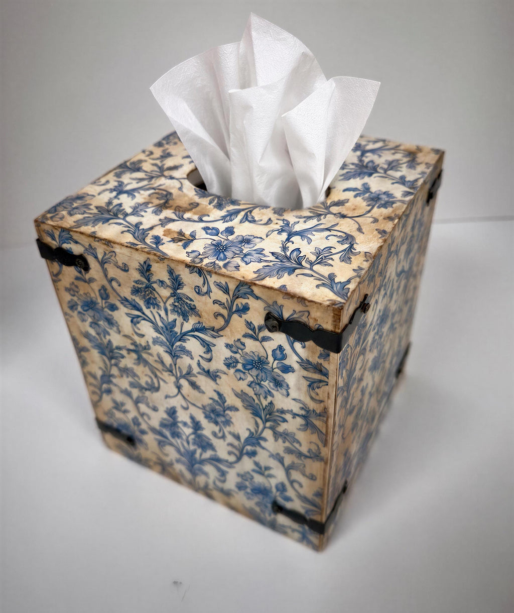 An old, ornate tissue box with a floral pattern and a white tissue paper dispenser.