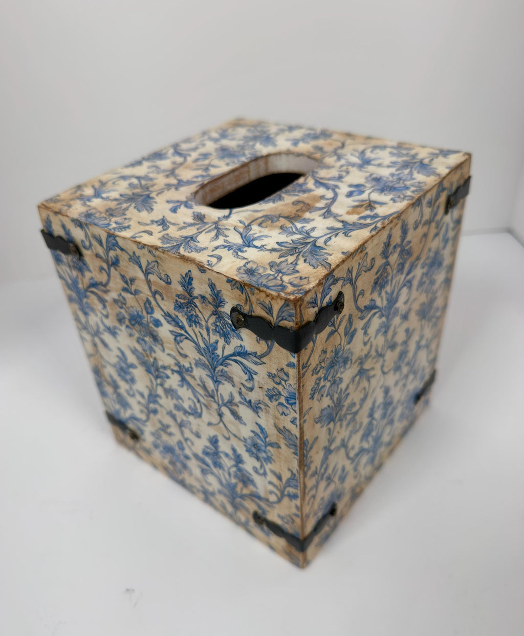 A wooden tissue box with a blue floral pattern on its surface.
