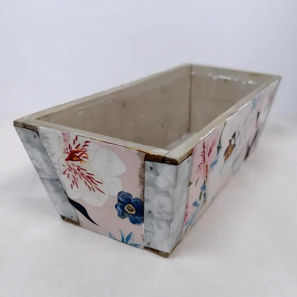 A rectangular, empty planter box with a floral pattern on its sides.