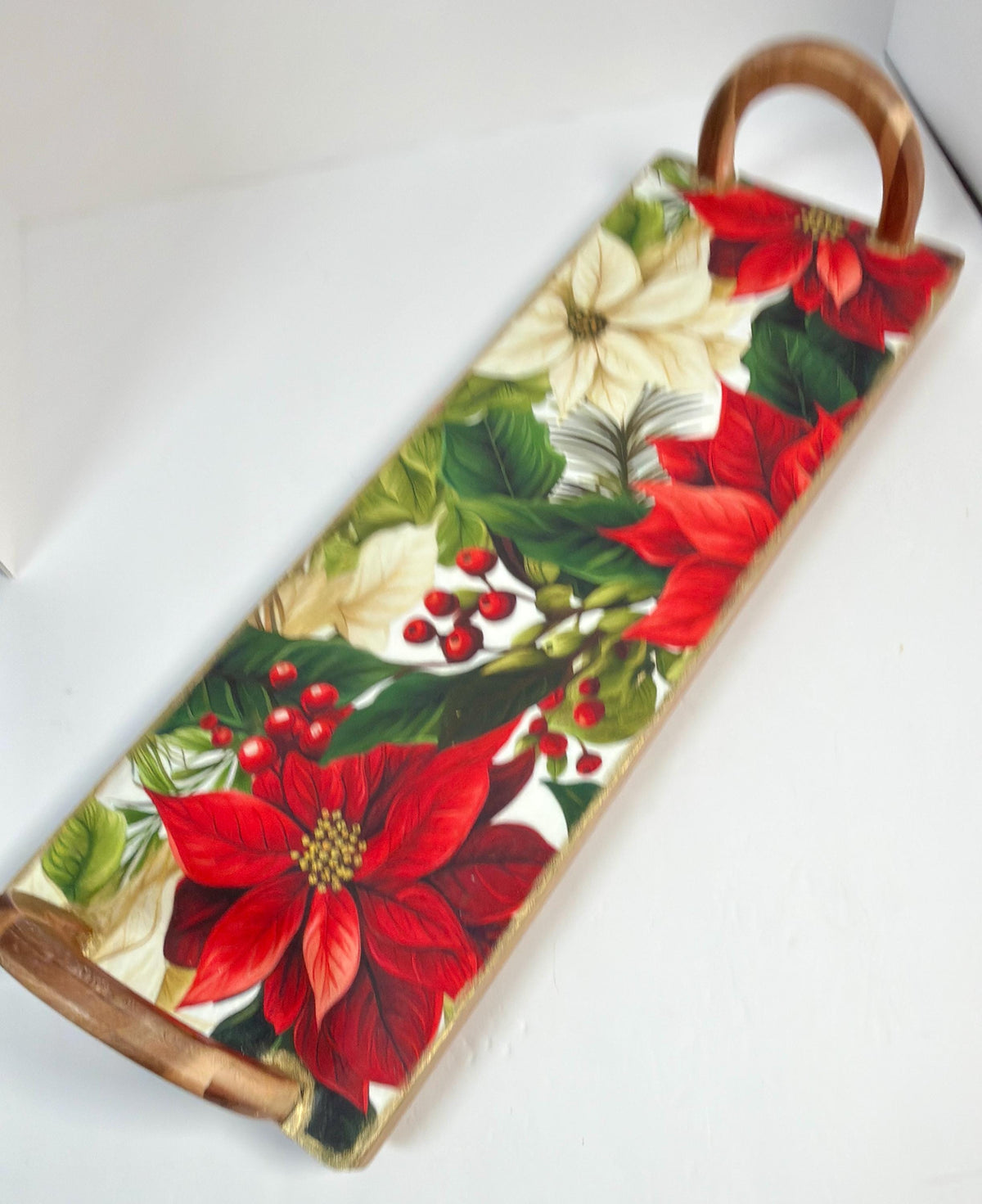 A decorative wooden tray with a floral pattern of red poinsettia flowers and green leaves.