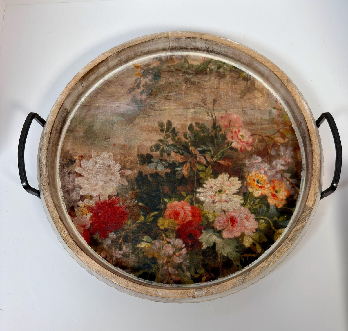 a round wooden tray with a floral design on it.