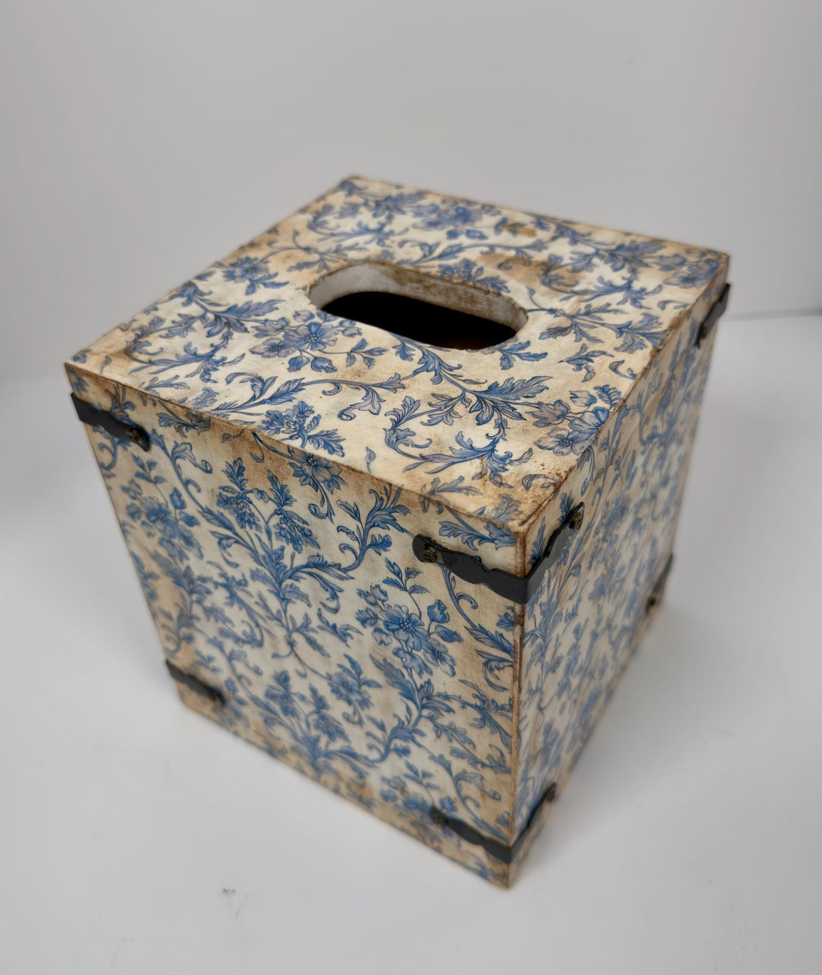 An old, weathered wooden box with a blue floral pattern on its surface.