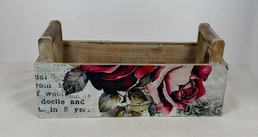 A wooden crate with a floral design on it, featuring a combination of red and pink roses.