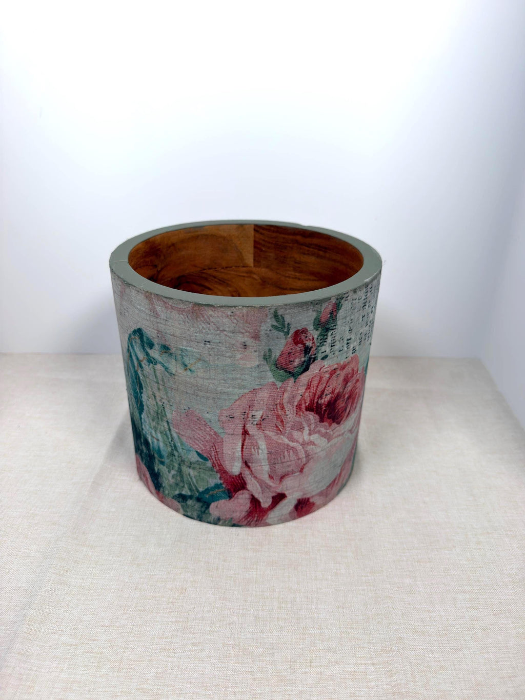a cylindrical object with a floral pattern on it, placed on a white surface.