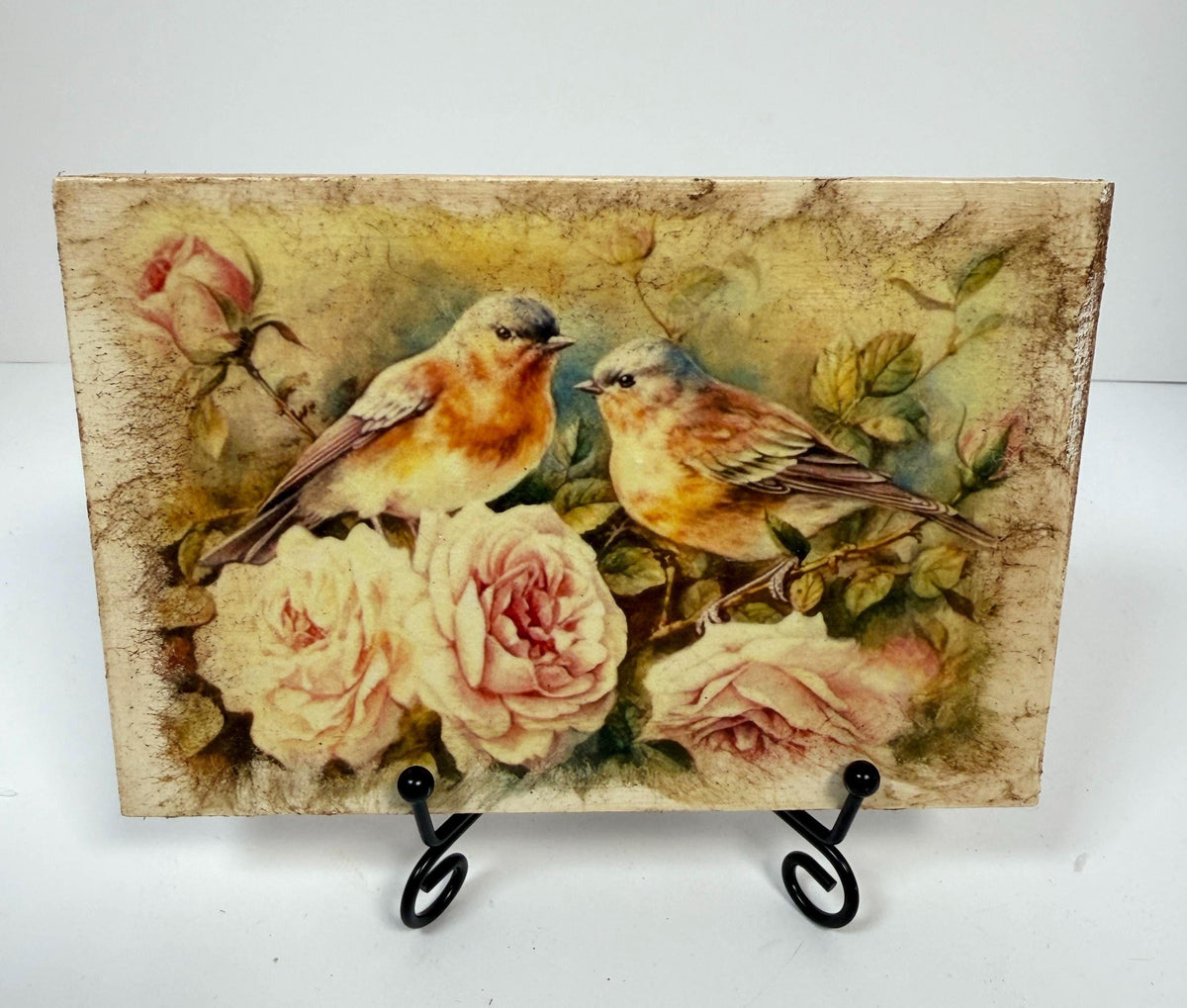 two birds perched on branches with pink roses in the background.