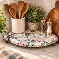 A kitchen counter with a floral patterned tray holding various kitchen utensils, including wooden spoons and a salt and pepper shaker.
