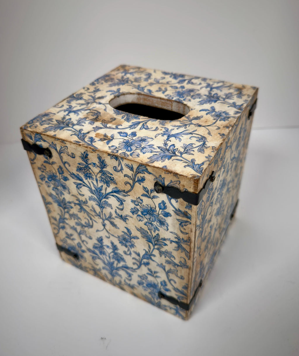 An old, weathered wooden box with a blue floral pattern on its surface.