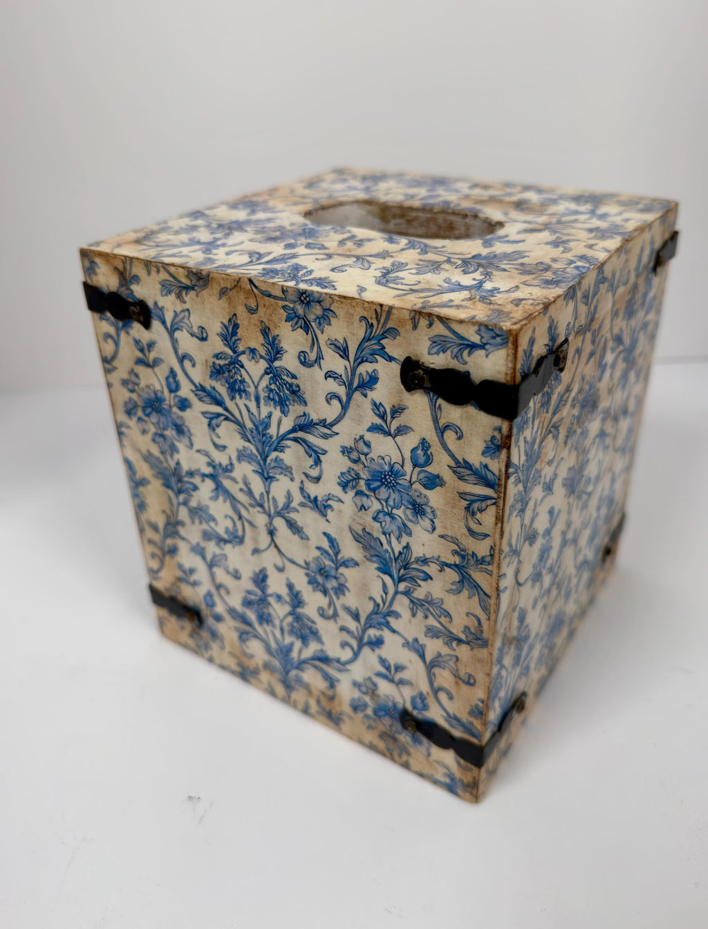 An old, weathered wooden box with a blue floral pattern on its surface.