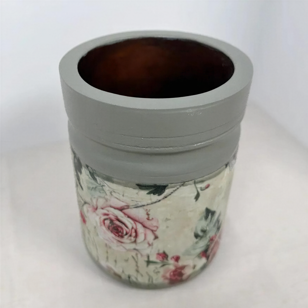 A gray vase with a floral pattern on it, placed on a white surface.