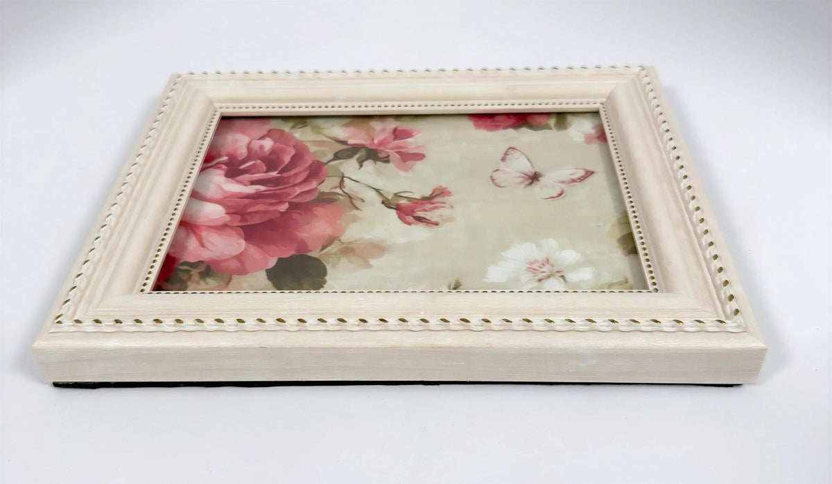 A square white picture frame with a floral design inside, featuring a large pink rose and smaller white flowers.