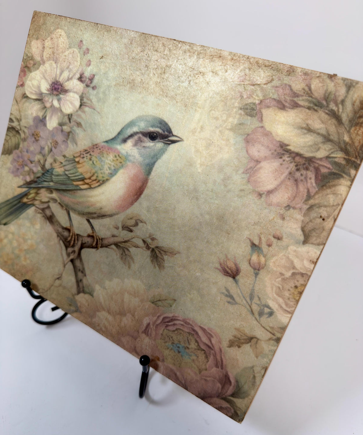 a vintage-style painting of a colorful bird perched on a branch, surrounded by flowers and foliage.