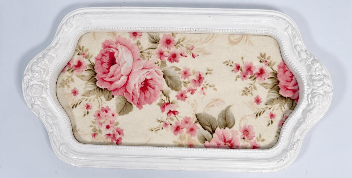 A white decorative tray with a floral pattern on the fabric covering it.