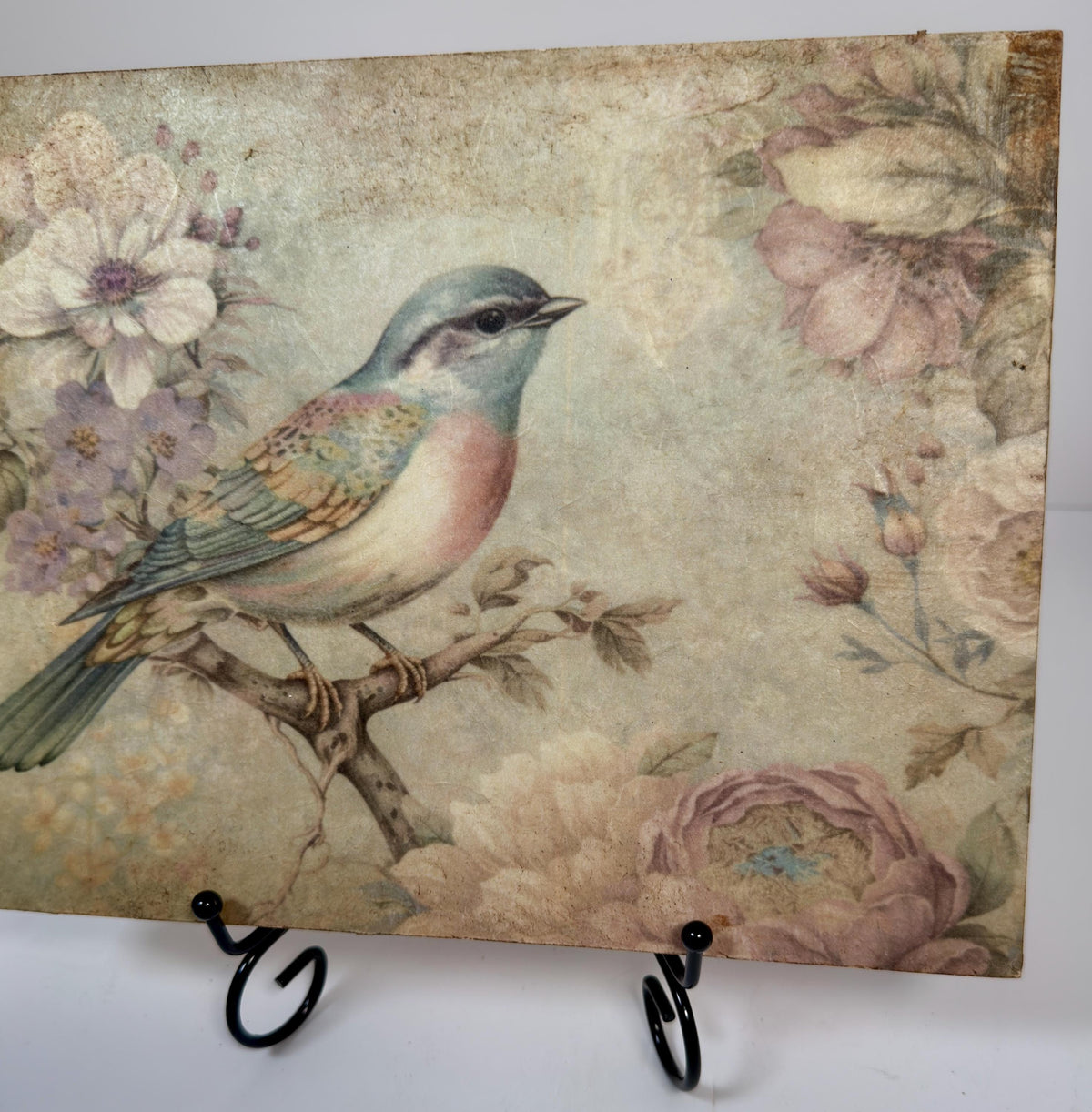 a vintage-style painting of a colorful bird perched on a branch, surrounded by flowers and foliage.