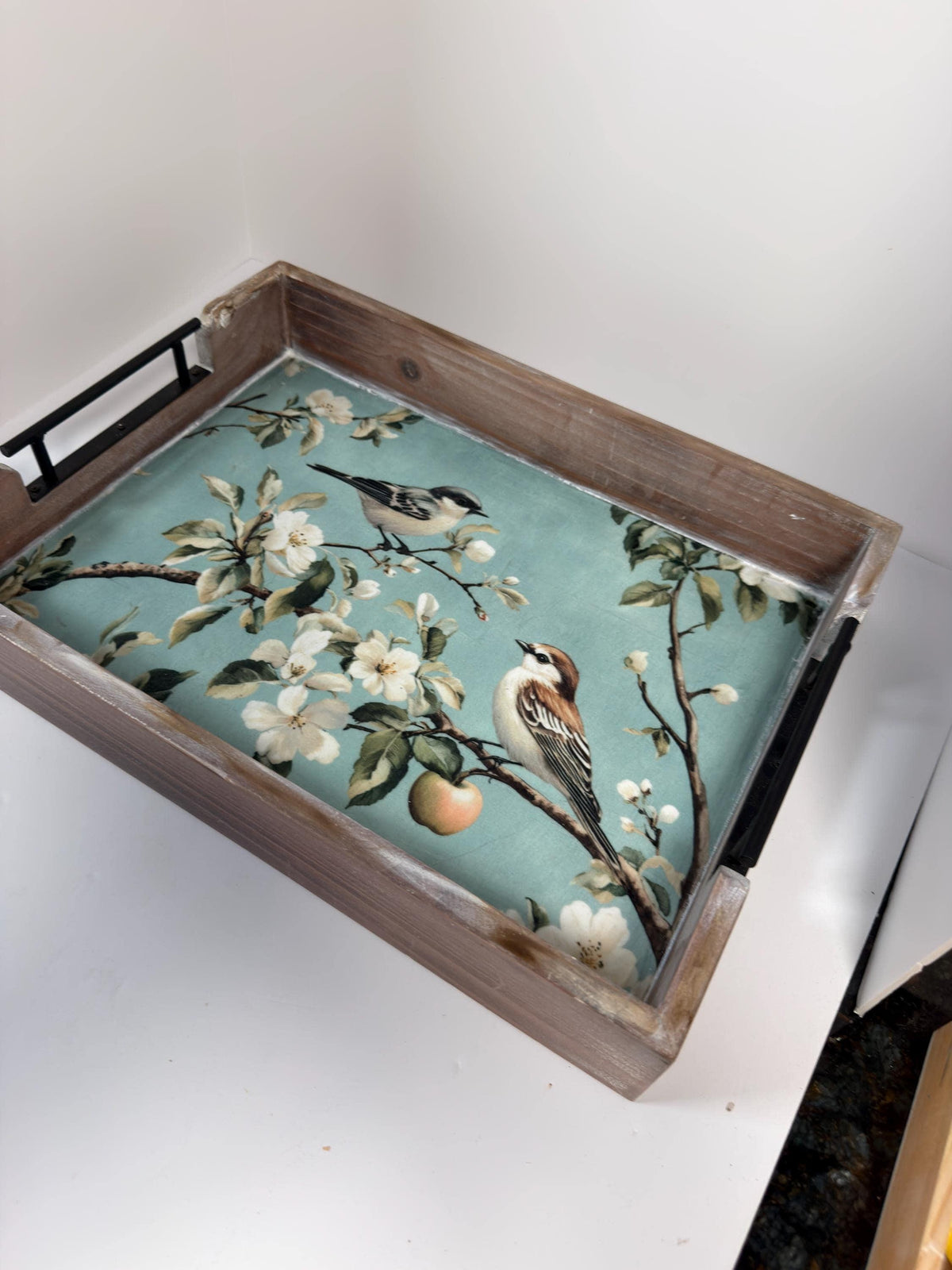 A wooden tray with a floral pattern on it, featuring a bird perched on a branch with flowers.