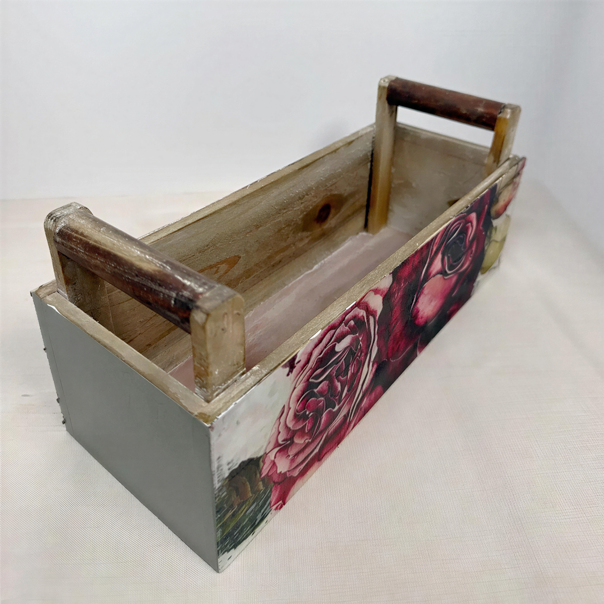 A wooden box with a floral design on the front, featuring a rose and other flowers.