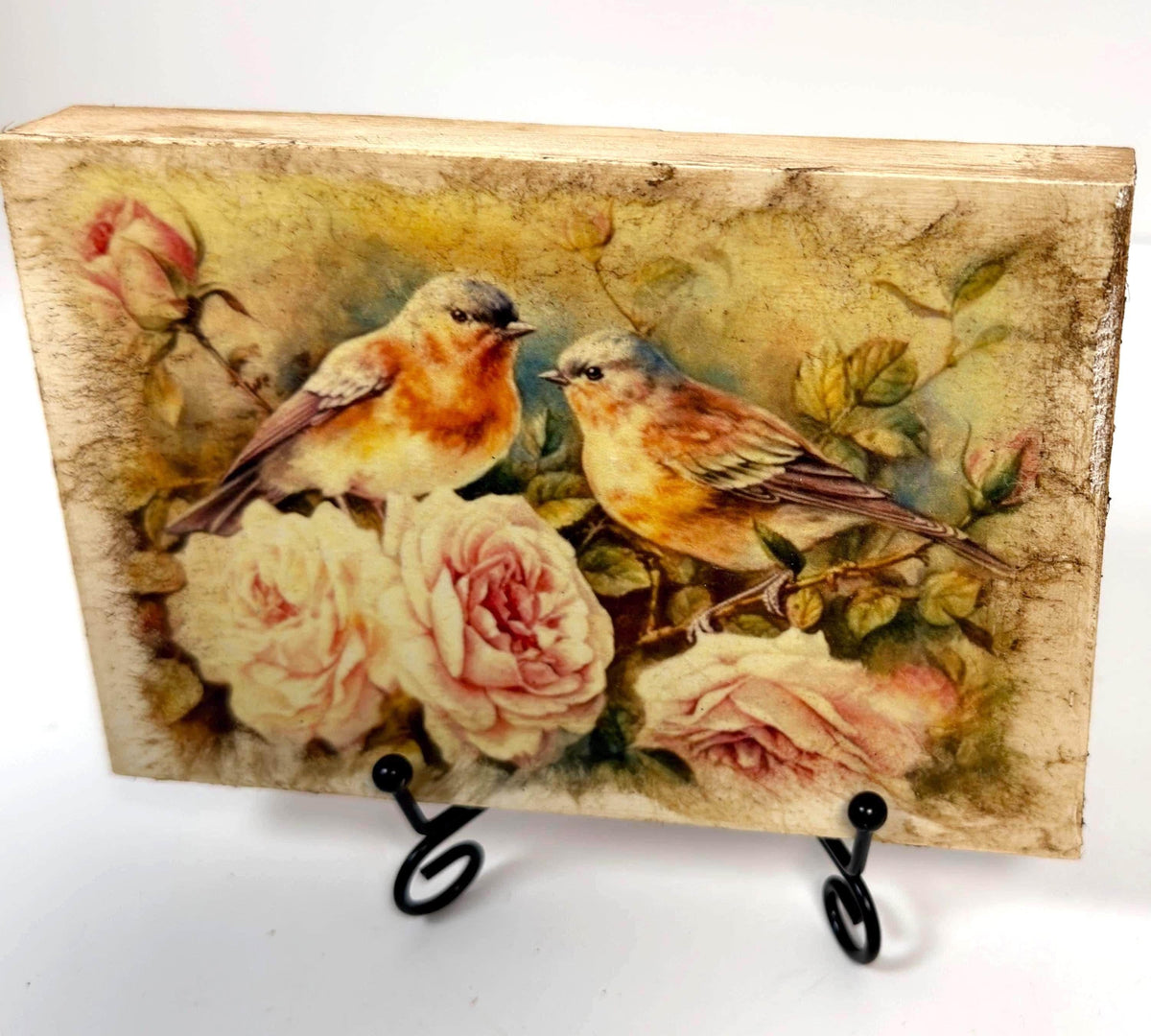 two birds perched on a branch with pink roses, surrounded by lush greenery.