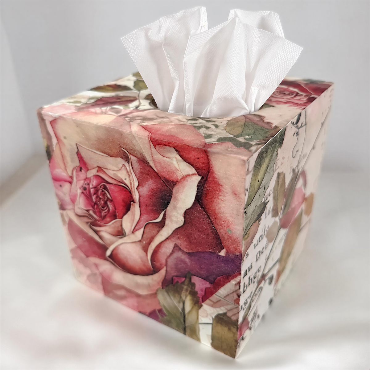 A decorative tissue box with a floral pattern and a white tissue paper dispenser.