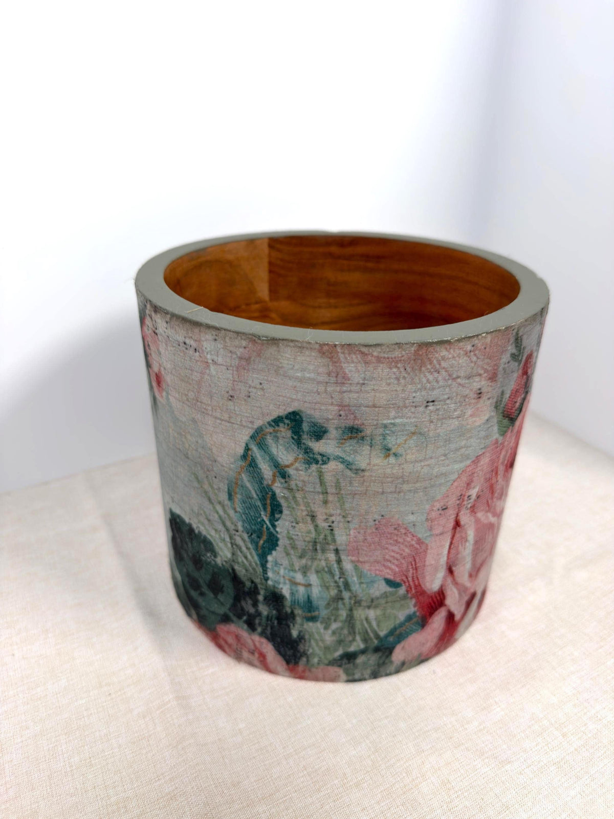 a ceramic vase with a floral pattern painted on it, sitting on a white surface.