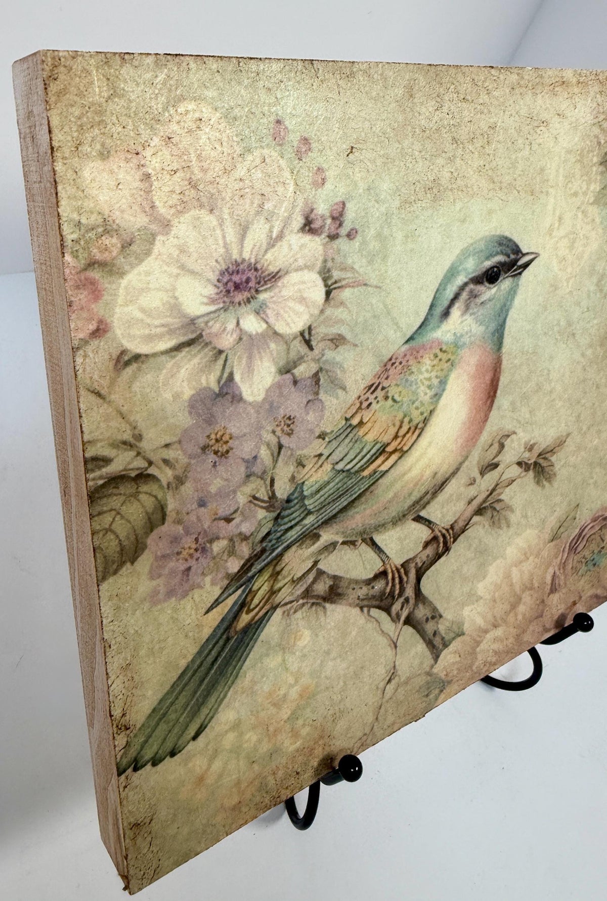 a wooden frame with a painting of a colorful bird perched on a branch, surrounded by flowers.
