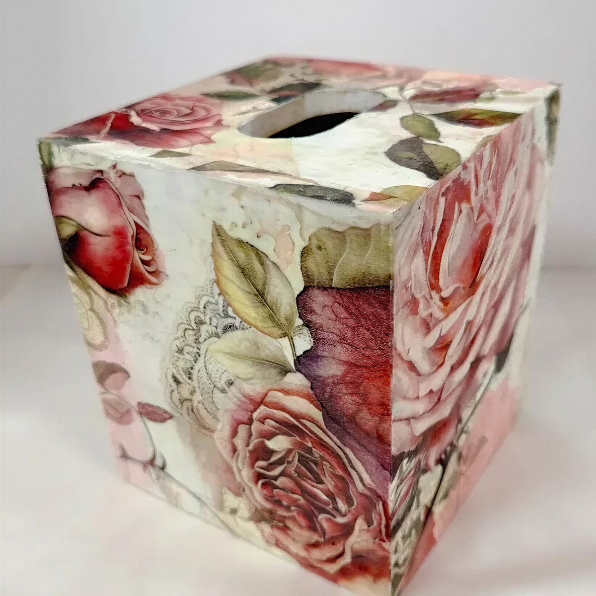 A decorative box cover with a floral pattern featuring roses and leaves.