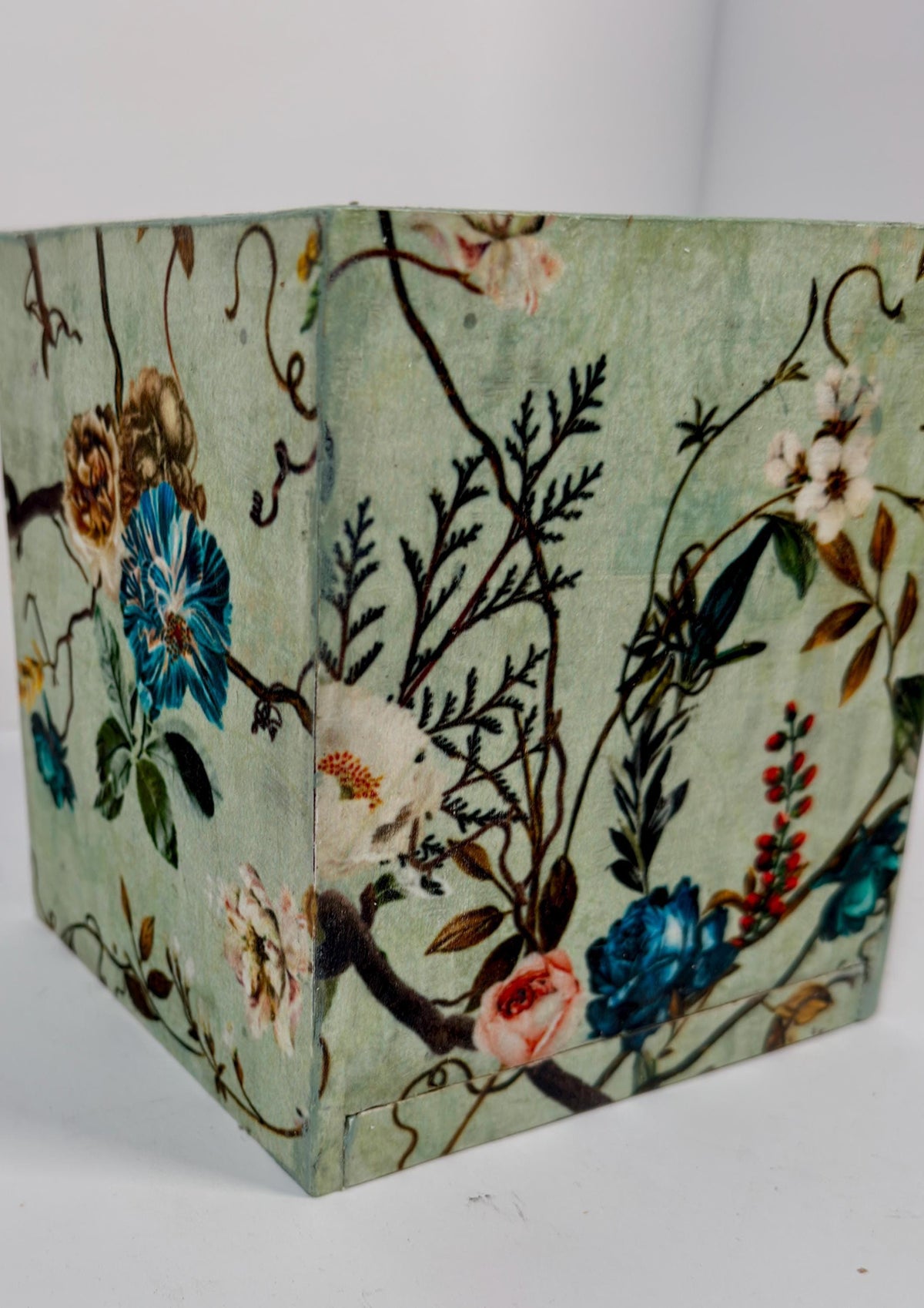 a square-shaped object with a floral pattern on it, including various flowers and leaves in different colors.