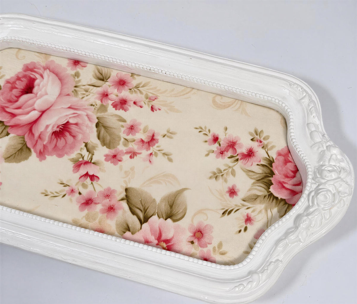 A white decorative tray with a floral pattern on it.