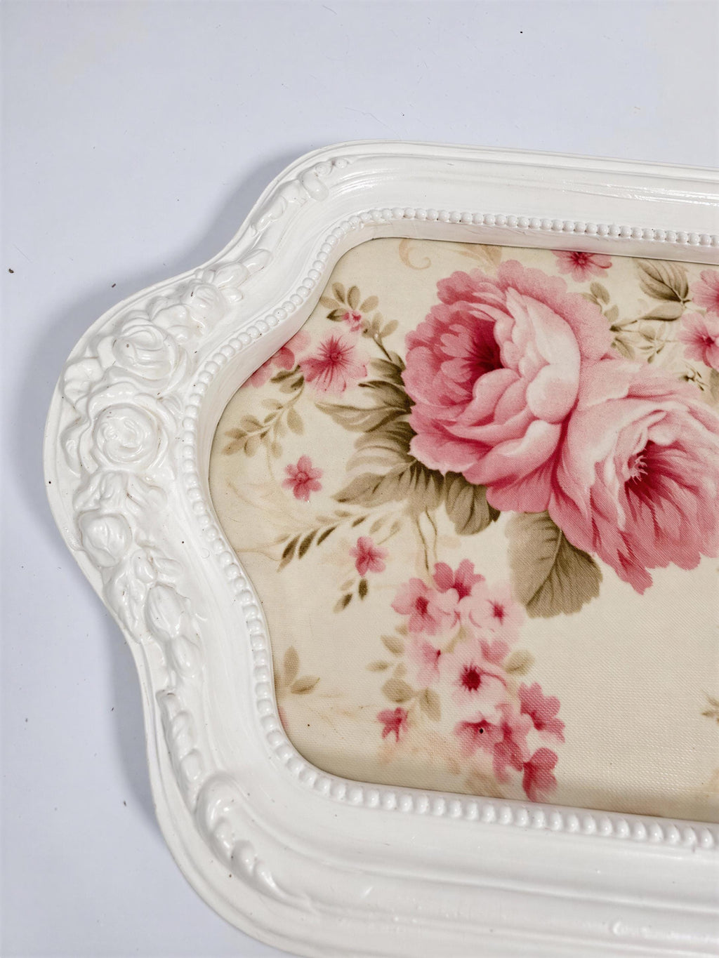 A white decorative tray with a floral pattern on the surface.