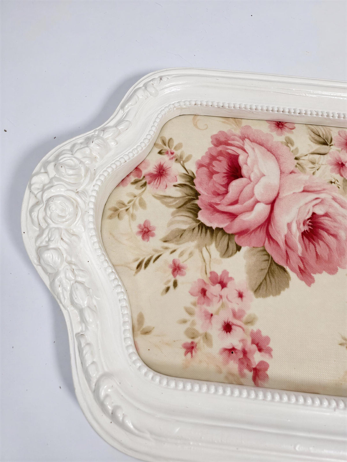 A white decorative tray with a floral pattern on the surface.