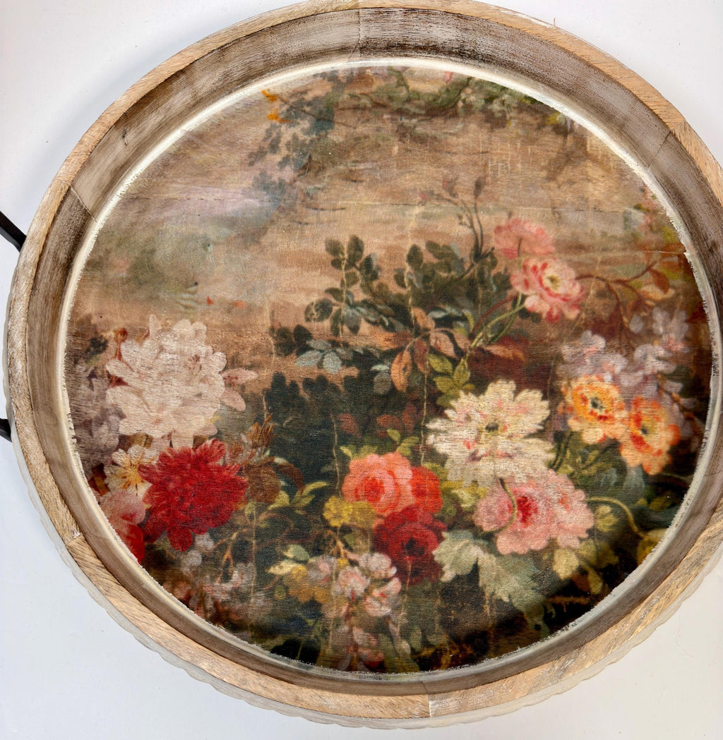 a round wooden tray with a floral painting on it.