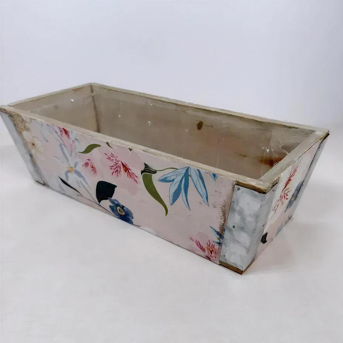A rectangular, empty planter box with a floral pattern on its side.