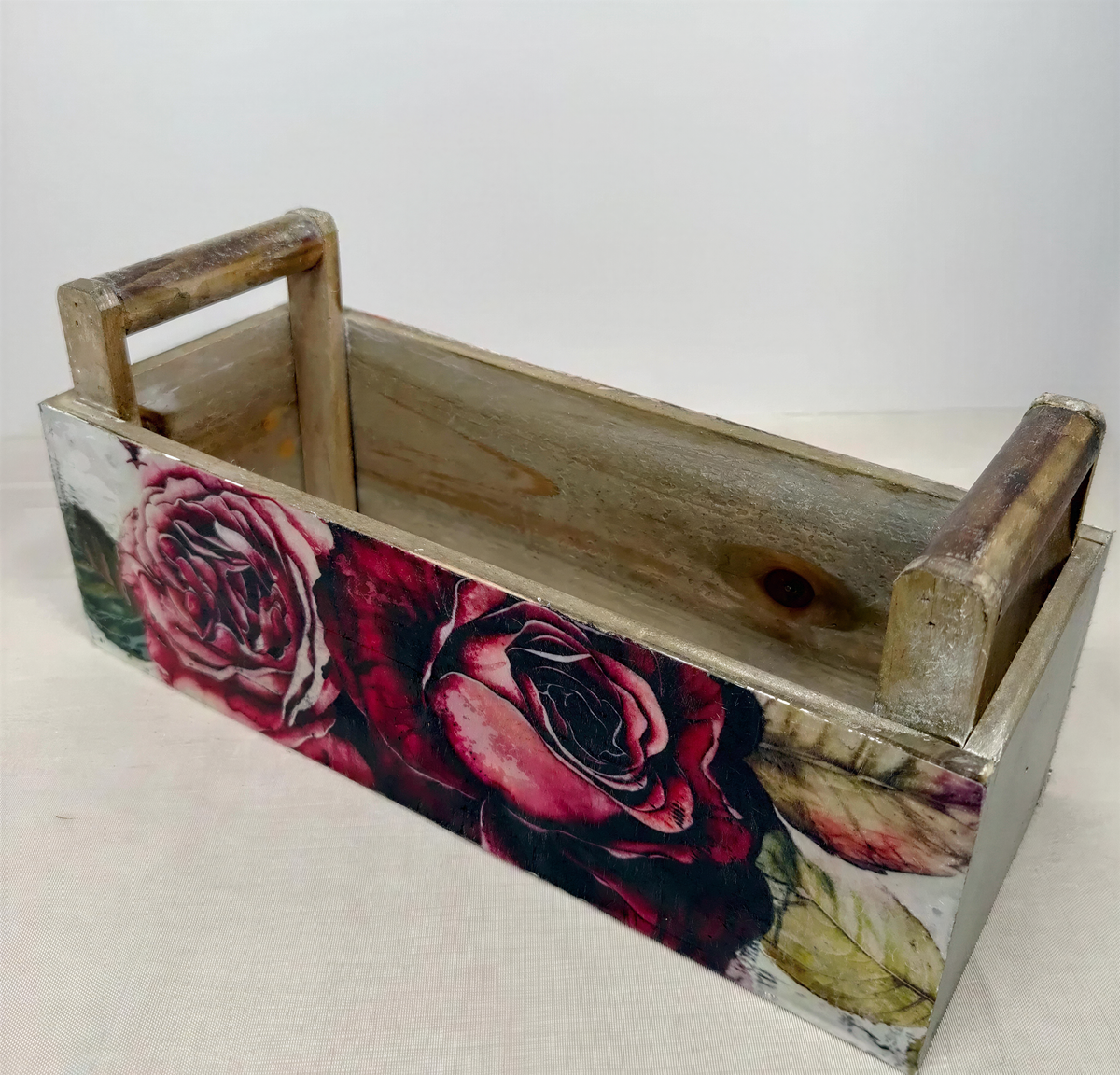 A wooden box with a floral design on the front, featuring a large red rose and other flowers.