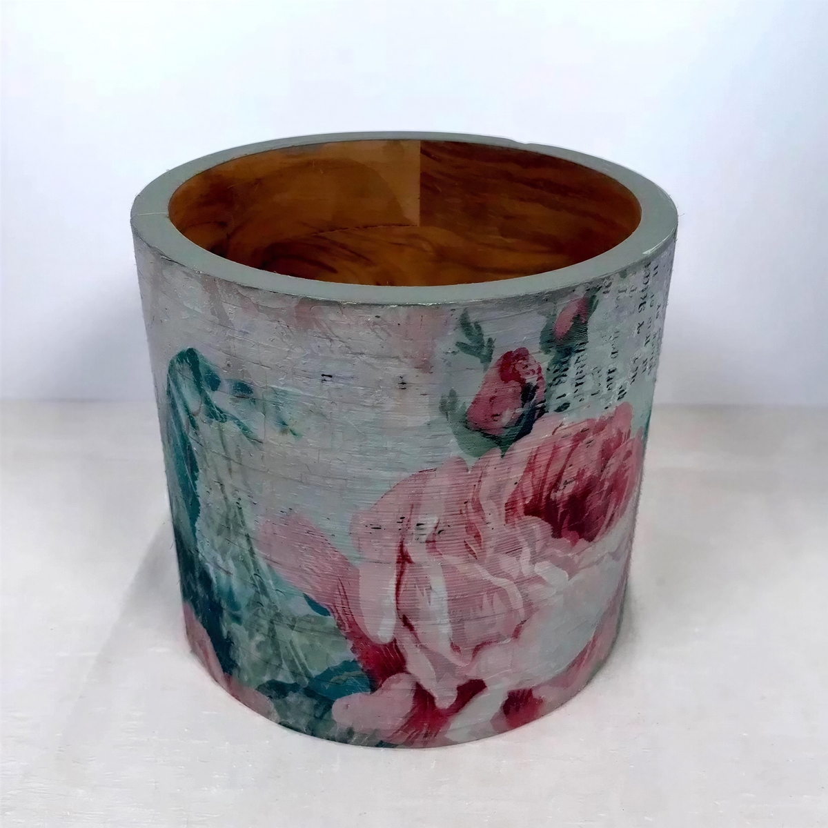 a cylindrical container with a floral pattern painted on it.