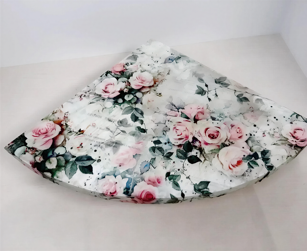 a decorative piece with a floral pattern, including pink roses and green leaves, on a white surface.