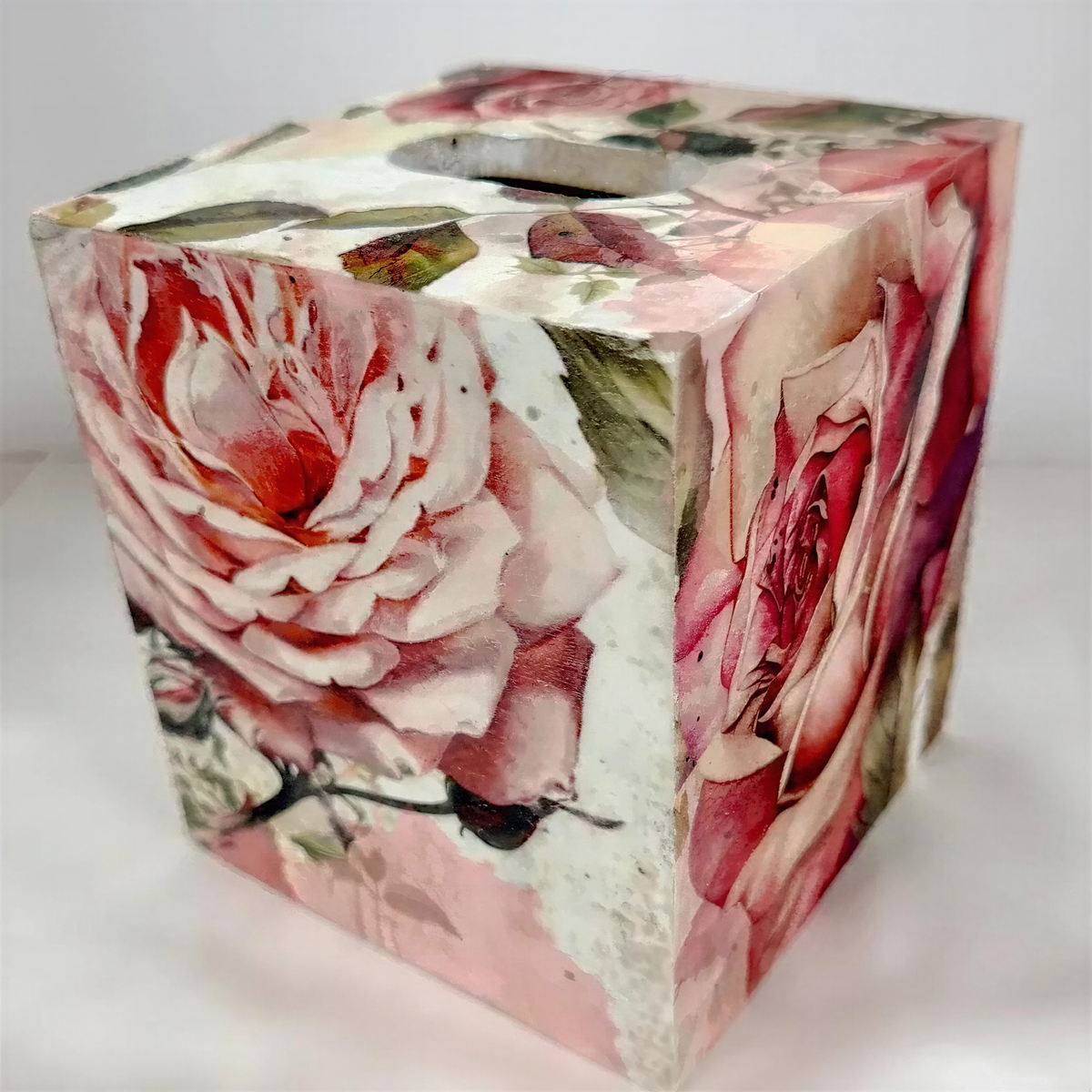 a wooden box with a floral pattern on it, including a large pink rose and other flowers.