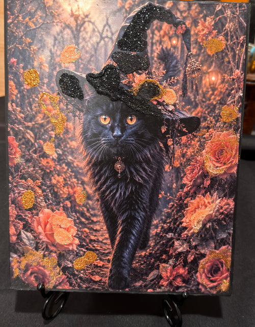 A black cat wearing a witch's hat, surrounded by a colorful garden with orange and pink flowers.