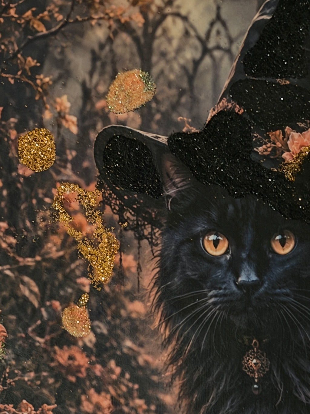 A close-up of a black cat with large, piercing eyes, wearing a black witch's hat decorated with gold glitter and flowers, set against a blurred background of foliage.
