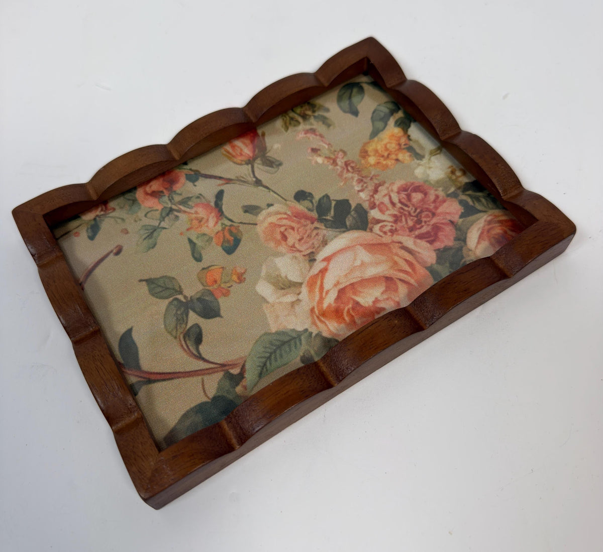 A wooden tray with a floral pattern on it, placed on a white surface.