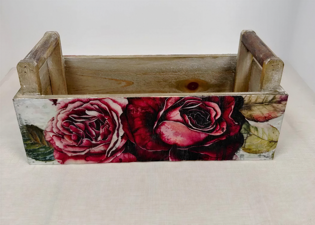 A wooden crate with a floral design featuring two large red roses on a white background.