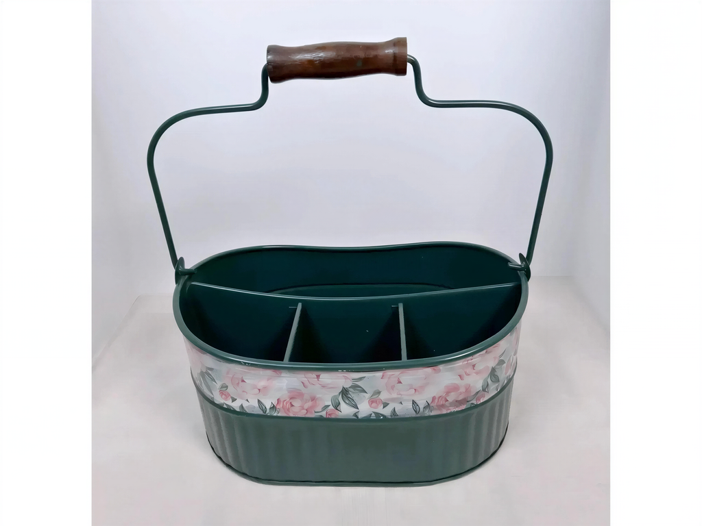 A green metal basket with a floral pattern on the front, featuring a handle and divided compartments.