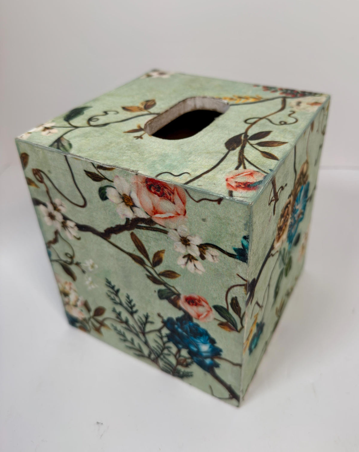 A square-shaped tissue box with a floral pattern on its surface.